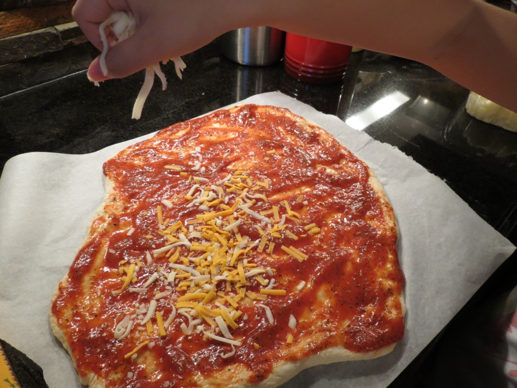 Sprinkling ingredients is a task we're learning to master.  Whether it's a sprinkling of herbs on meat, or salt in a dish, or cheese on a pizza, this skill takes a bit of time.  But it's fun!  And we get to eat some shredded cheese too...cook's privilege, you know.